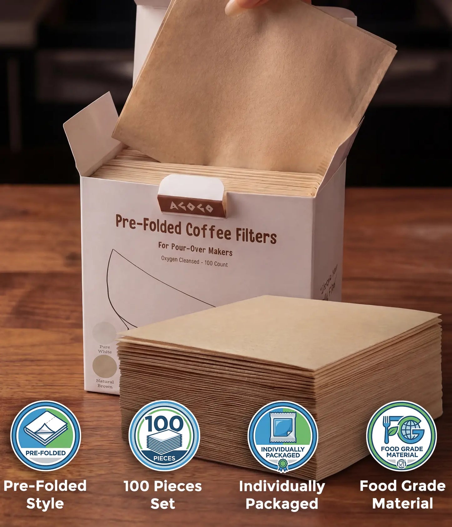 A hand taking a natural brown square coffee filter from the AGOGO 100-count value box, with a stack of pre-folded filters resting on a wooden table.