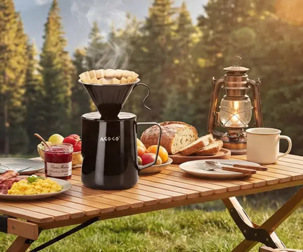 AGOGO black stainless steel camping pour over coffee maker steaming on a wooden picnic table during an outdoor forest camp adventure.