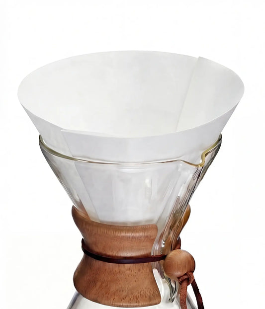 A pure white 25cm circle pre-folded coffee filter sitting perfectly inside a classic glass pour-over coffee maker.