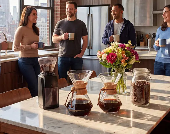Colleagues enjoying a premium coffee break around a marble island in a modern office workspace, featuring two AGOGO Diamond glass pour over carafes.