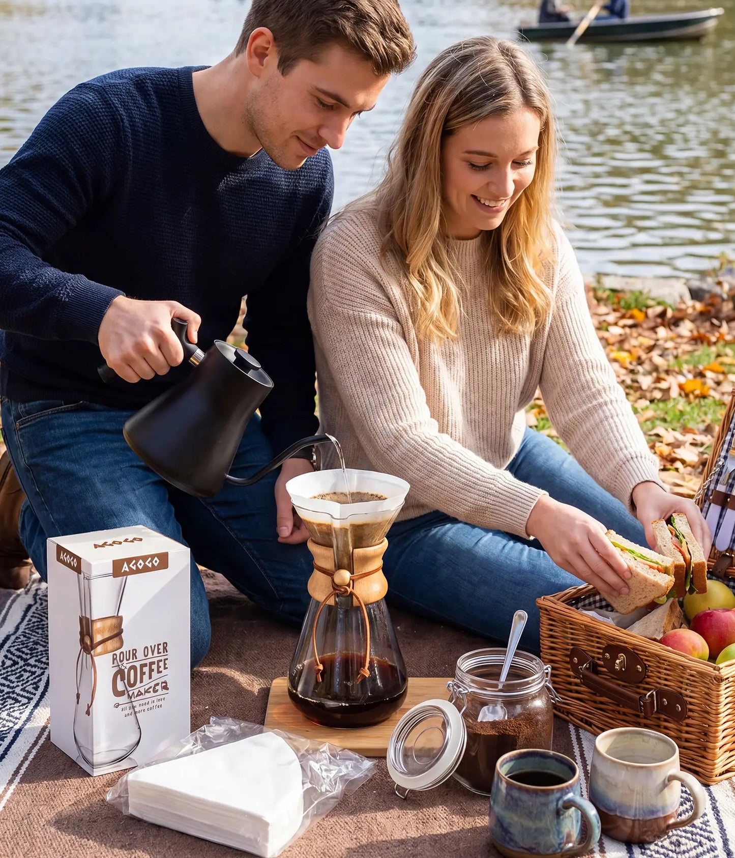 Couple enjoying a lakeside picnic, brewing fresh coffee with the portable AGOGO 600ml pour over maker, featuring the minimalist packaging and premium paper filters.