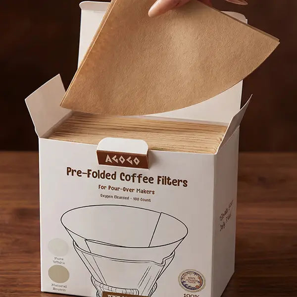 A hand gracefully pulling a natural brown 25cm circle pre-folded coffee filter from the AGOGO 100-count dispenser box.